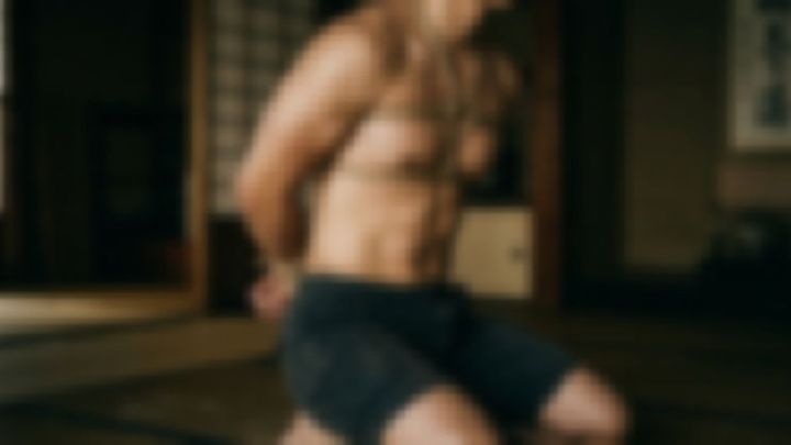 薄暗い和室で上半身を縄で縛られ、ひざまずく男性