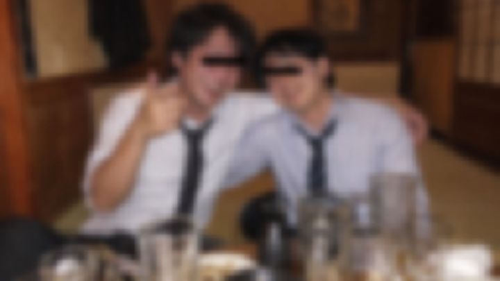 居酒屋の座敷でネクタイをゆるめて笑う男性2人