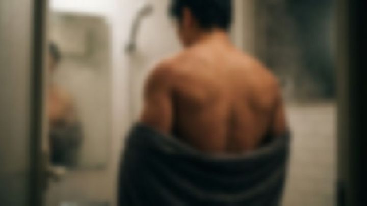 浴室の鏡の前に立つ、背中が見える男性