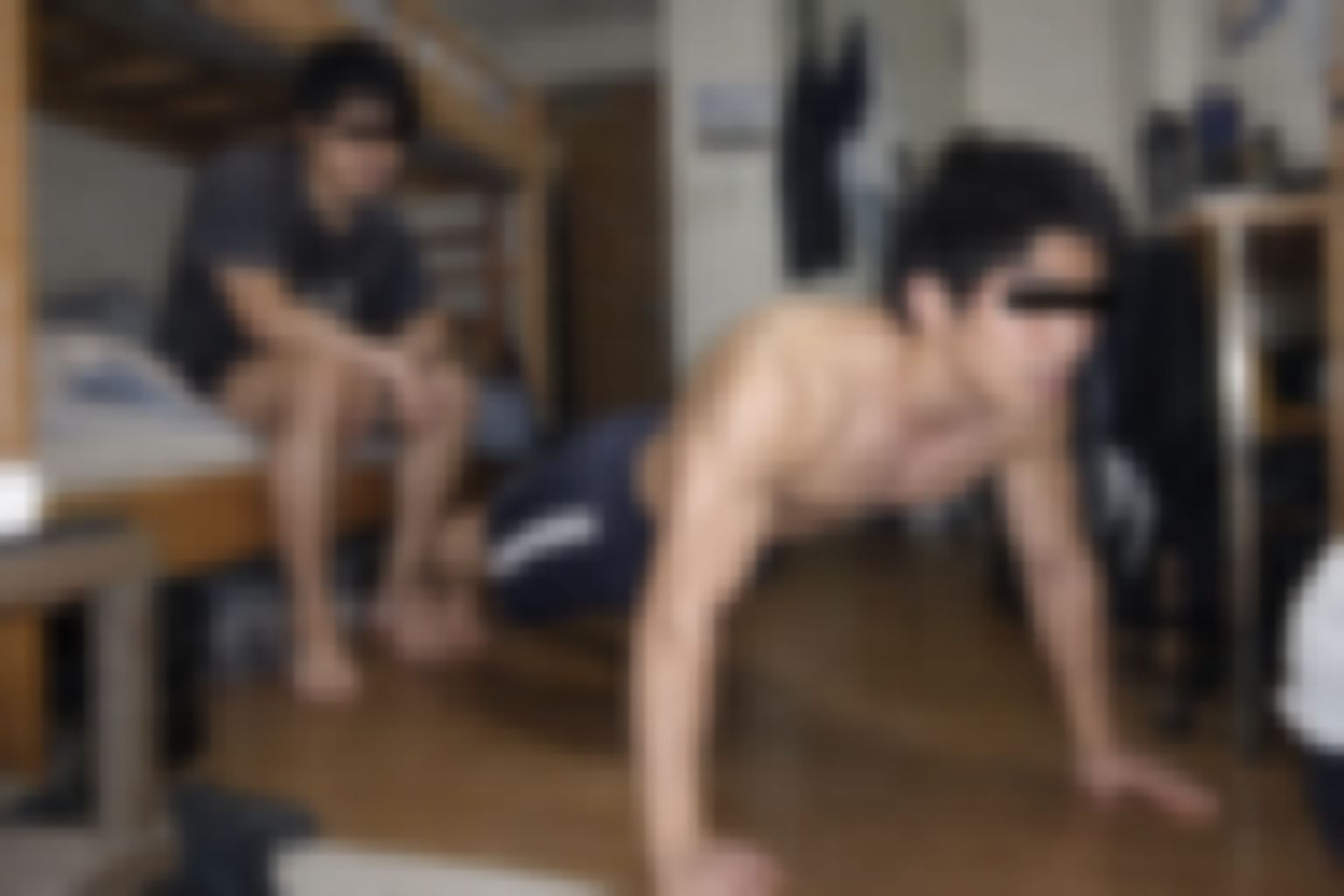 寮の部屋で腕立て伏せをする上半身裸の男性と、二段ベッドに座るルームメイト