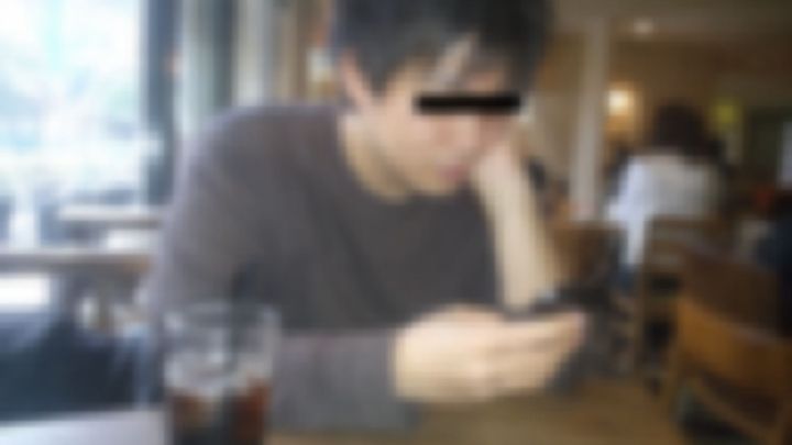 カフェでアイスコーヒーを前にスマホを見る男性