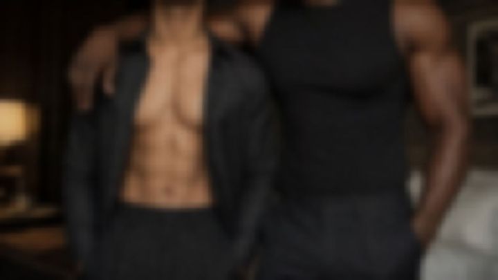 暗い室内で肩を組んで立つ、上半身裸と黒いタンクトップの男性二人