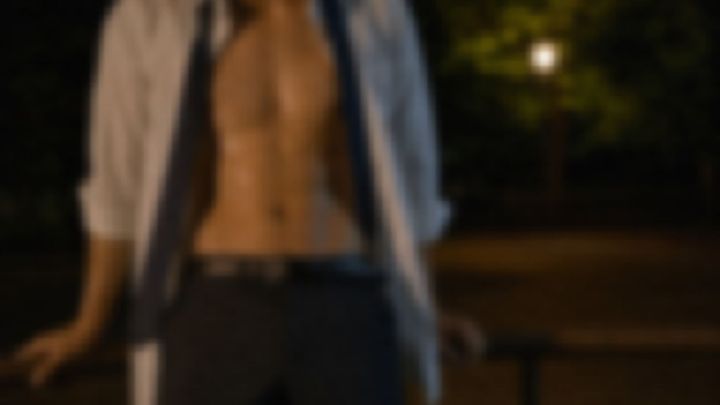 夜の公園で手すりにもたれる、白いシャツを開いた男性