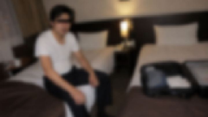 出張先のホテルのツインルームで肌着姿で座る男性