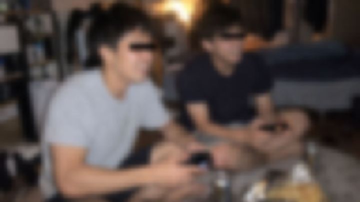 缶ビールを置いた床でゲームをする男性2人