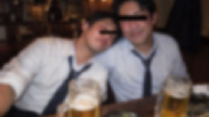 居酒屋で酔ってもたれ合うワイシャツ姿の男性2人