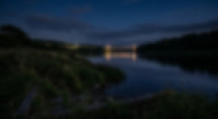 夜空の下、川面に明かりが映る橋の遠景