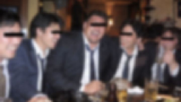 二次会のバーでネクタイをゆるめて盛り上がるスーツの男性たち